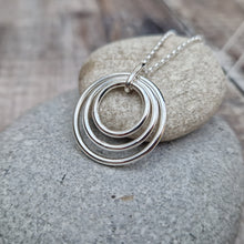 Load image into Gallery viewer, Sterling Silver three circle necklace. Three open silver concentric circles sat within each other, smallest in the centre. Attached to silver chain via small silver hoop. Largest circle measuring approximately 25mm diameter, smallest circle measuring approximately 15mm diameter. Chain length 16, 18 or 20 inches.