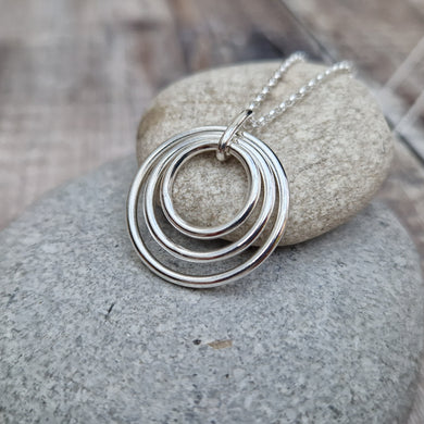 Sterling Silver three circle necklace. Three open silver concentric circles sat within each other, smallest in the centre. Attached to silver chain via small silver hoop. Largest circle measuring approximately 25mm diameter, smallest circle measuring approximately 15mm diameter. Chain length 16, 18 or 20 inches.