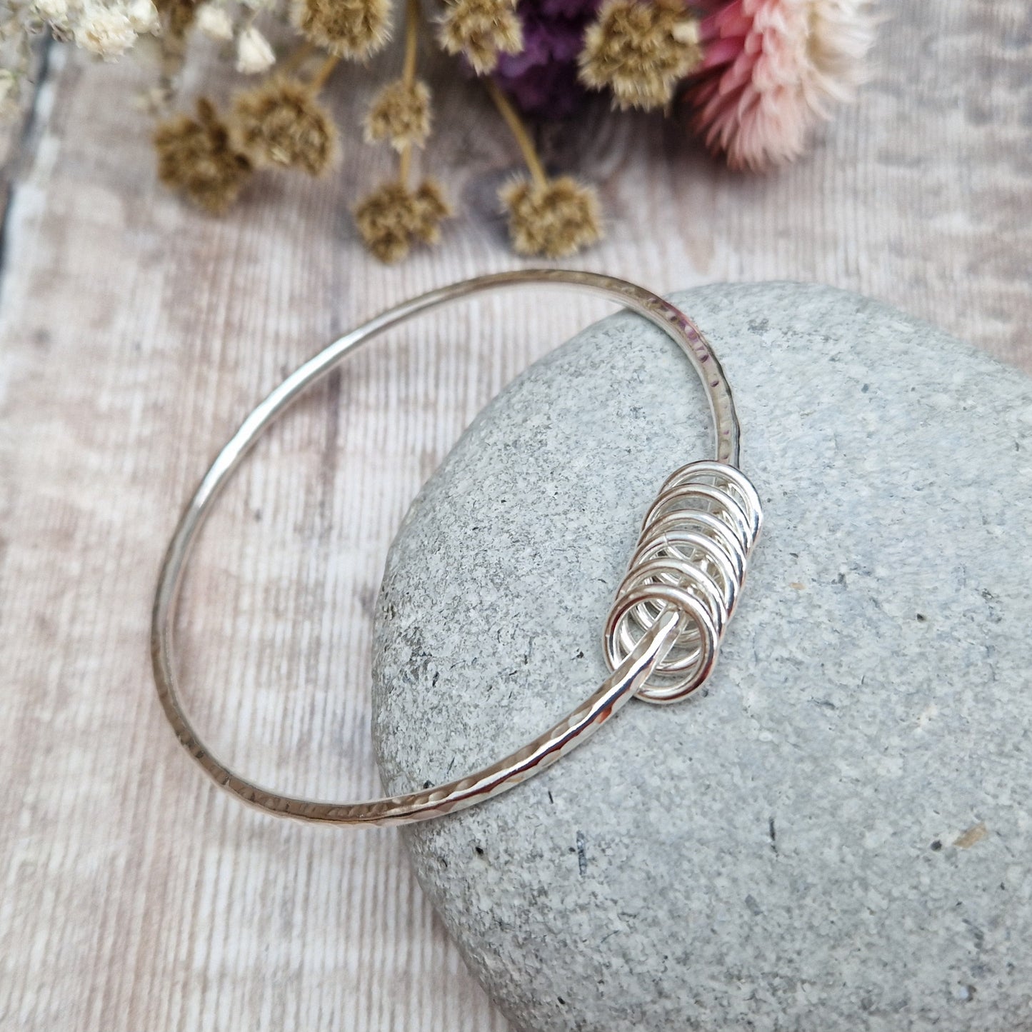 Sterling Silver hammered texture bangle passing through six silver open circles.