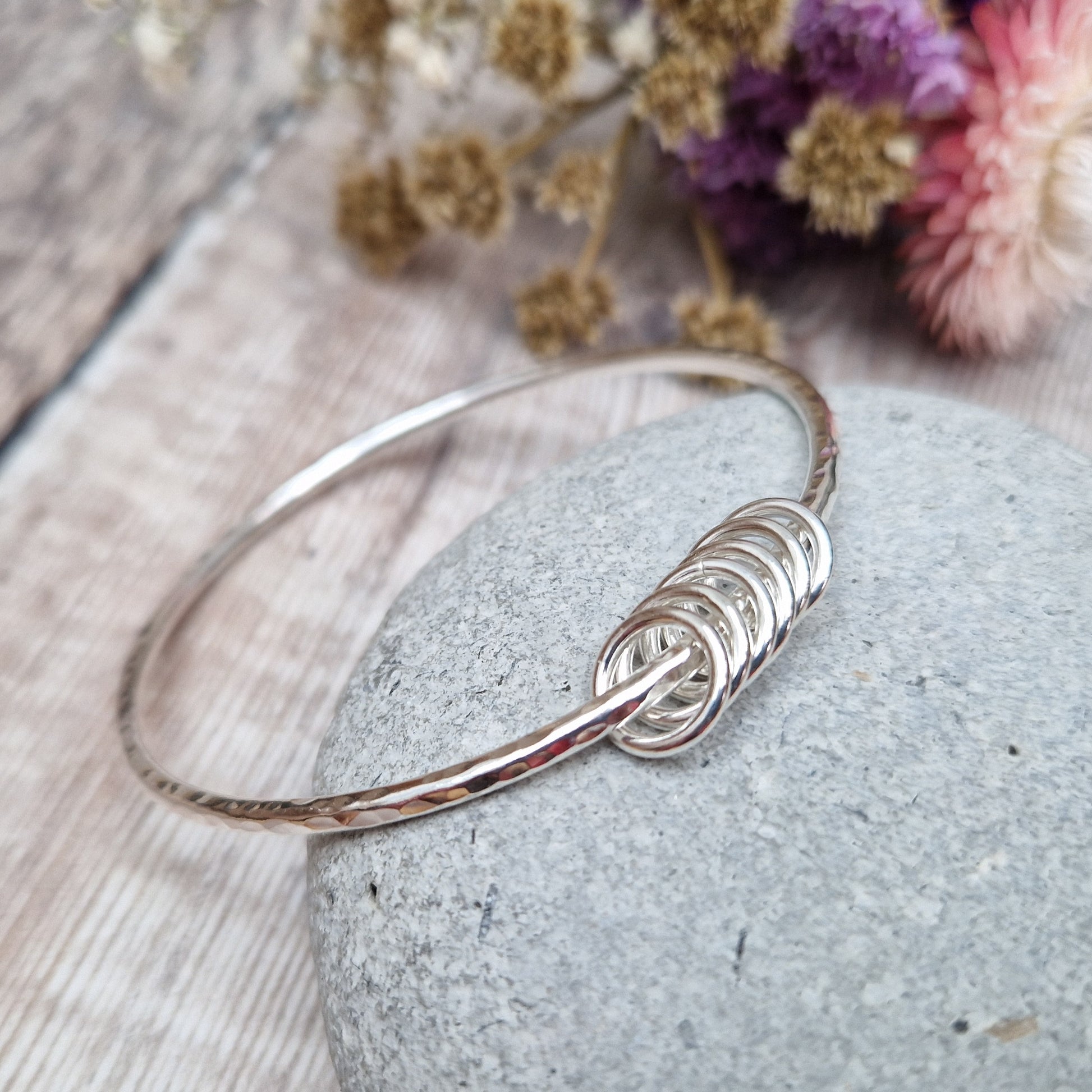 Sterling Silver hammered texture bangle passing through six silver open circles.
