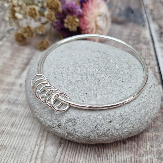 Sterling Silver hammered texture bangle passing through six silver open circles.