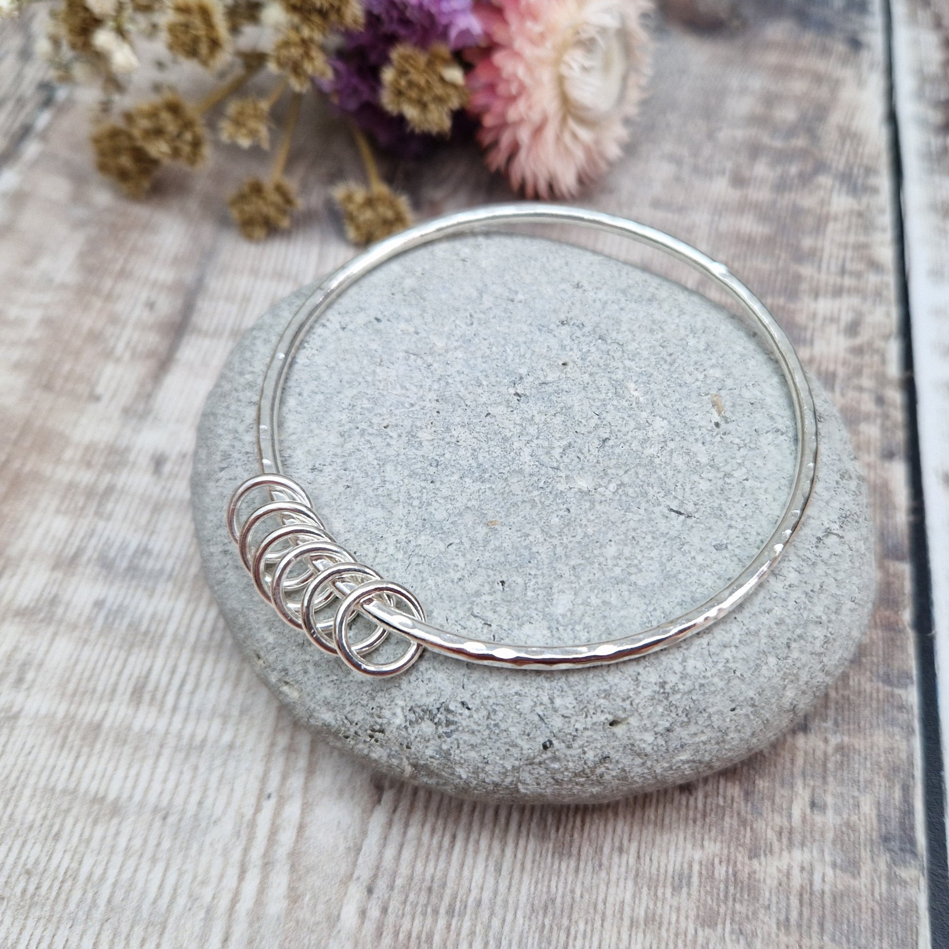 Sterling Silver hammered texture bangle passing through six silver open circles.
