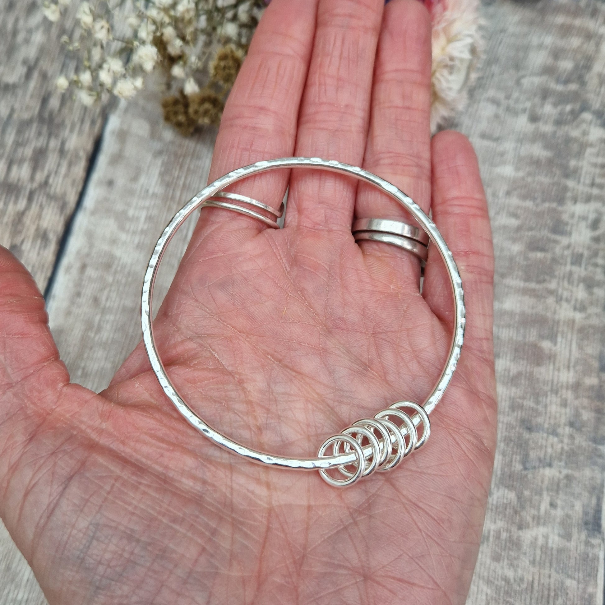 Sterling Silver hammered texture bangle passing through six silver open circles.