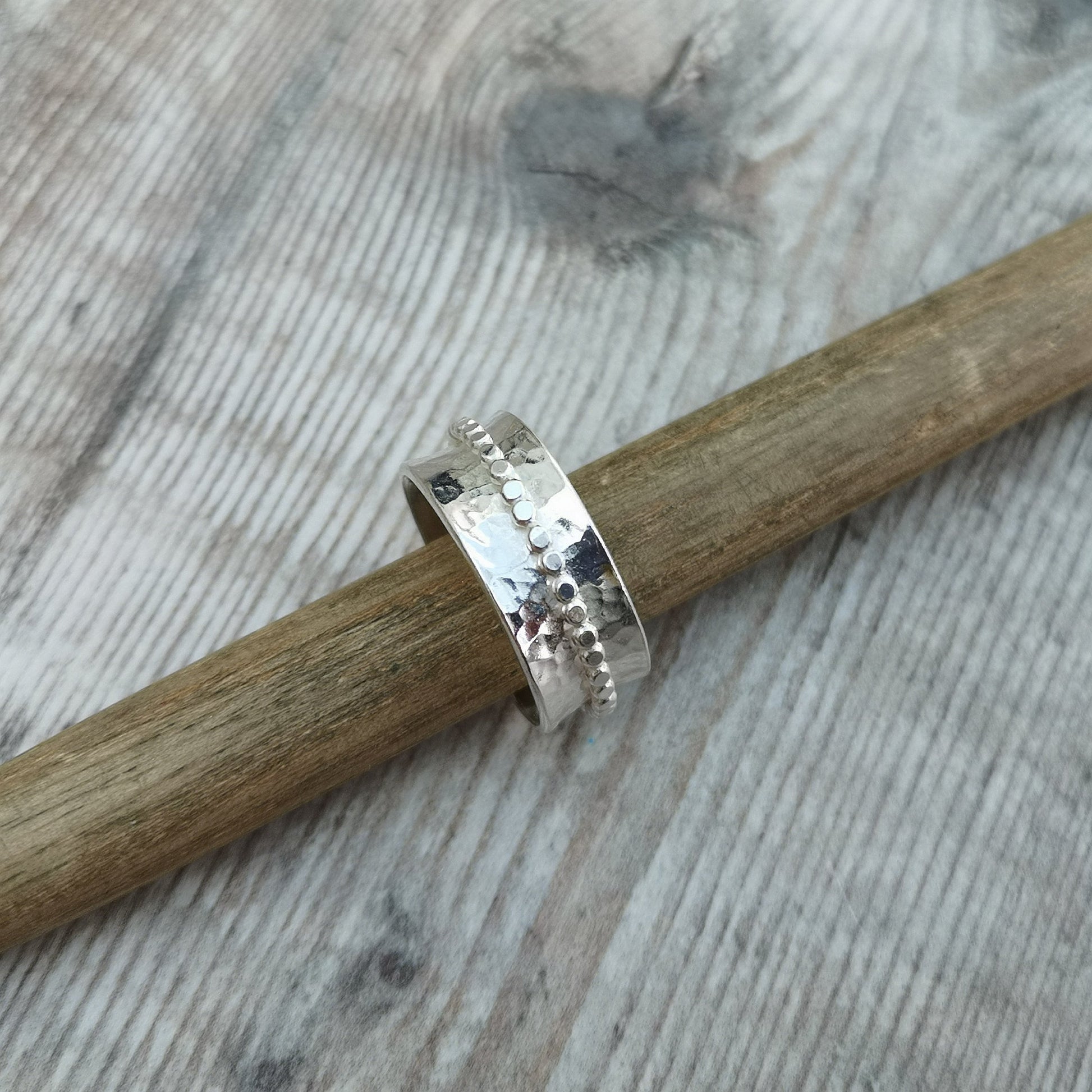 Approx. 8mm wide hammered texture silver band with additional 2mm wide silver beaded band around the middle that spins independently.