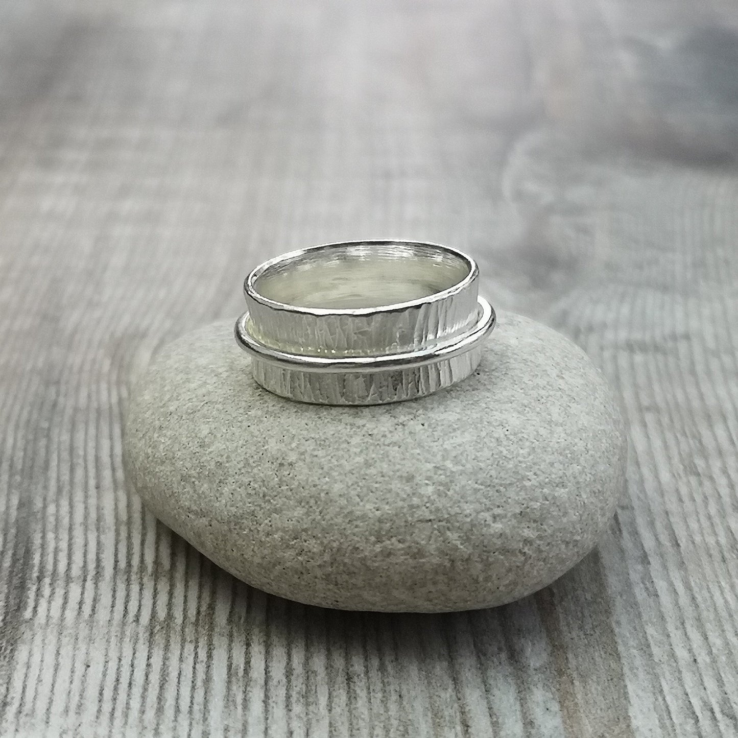 Approx. 8mm wide bark textured silver band with additional 2mm wide smooth silver band around the middle that spins independently.
