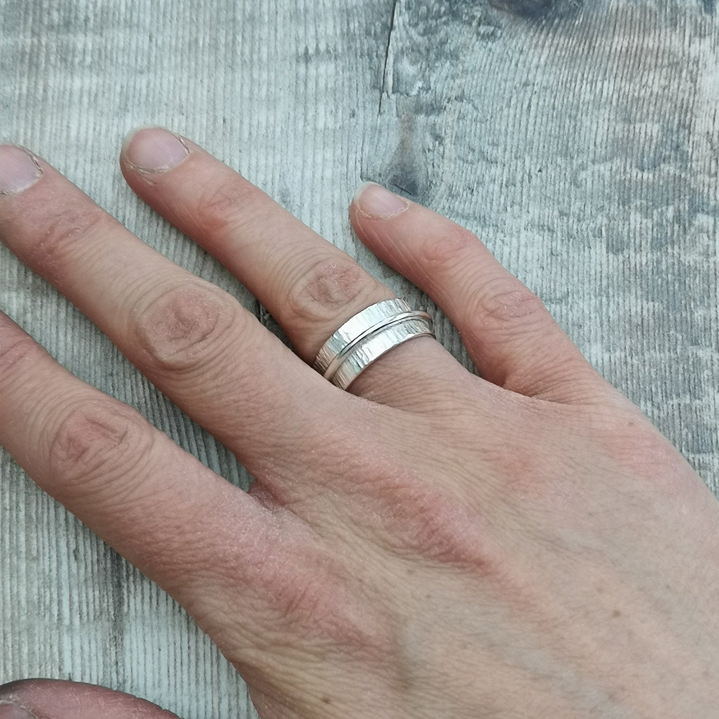 Approx. 8mm wide bark textured silver band with additional 2mm wide smooth silver band around the middle that spins independently.