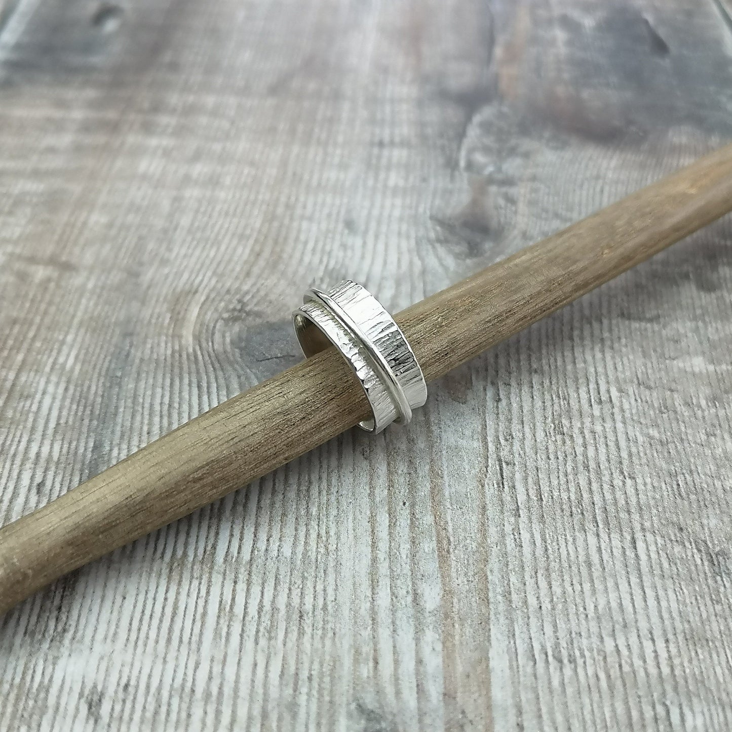 Approx. 8mm wide bark textured silver band with additional 2mm wide smooth silver band around the middle that spins independently.