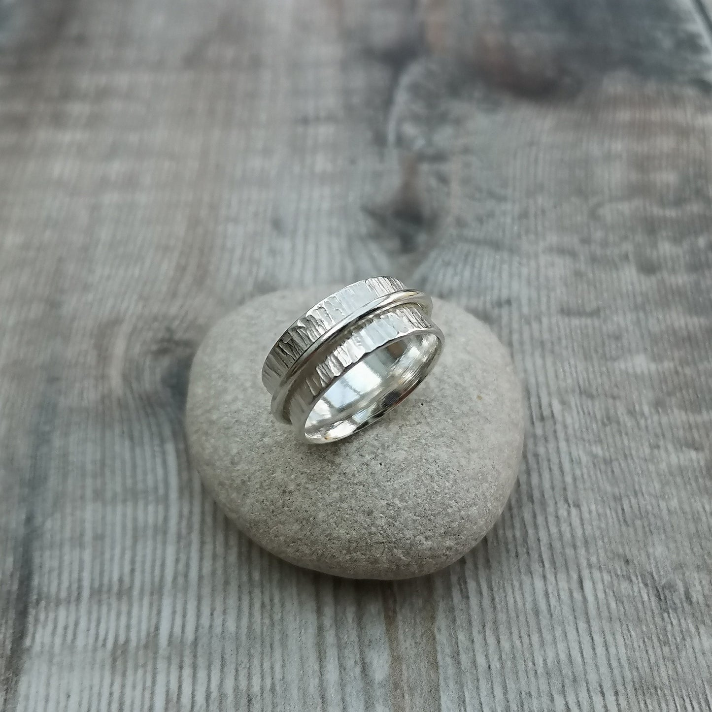 Approx. 8mm wide bark textured silver band with additional 2mm wide smooth silver band around the middle that spins independently.