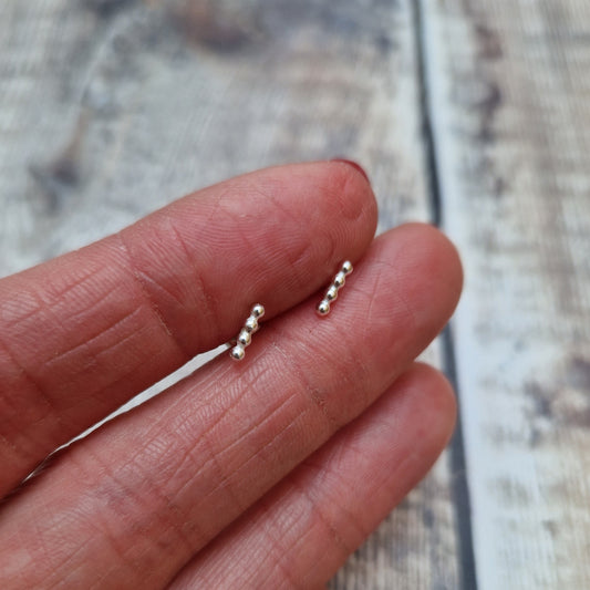 Each earring is four small Sterling Silver beads in a straight row attached to a silver stud bar.