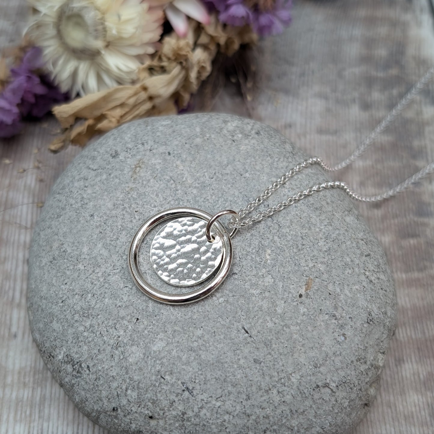 Sterling Silver smooth circle pendant with hammered silver disc sitting inside, suspended from a silver circle link attached to silver chain.