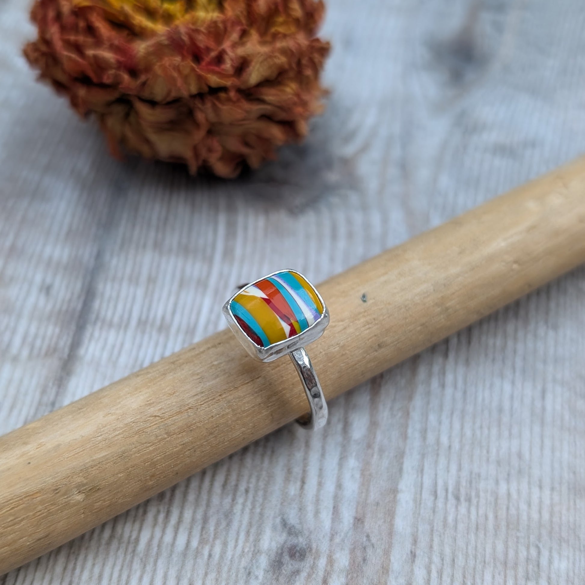 Rectangle Surfite ring displayed on a ring mandrel with a dried flower in the background.