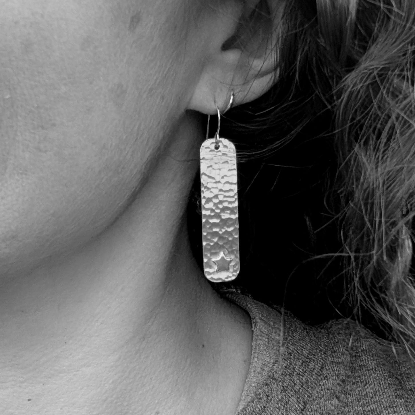 Copper hammered rectangle earrings with silver stars being worn, showing the length and how they hang from the ear.