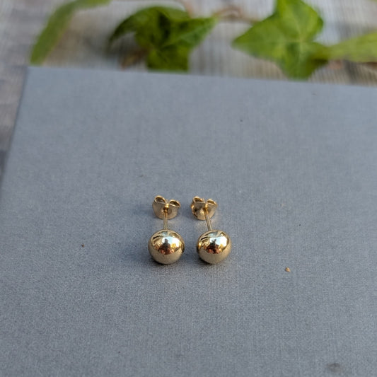 Handmade solid gold pebble stud earrings made from recycled 9ct gold, shown with their posts and butterfly backs on a grey background.
