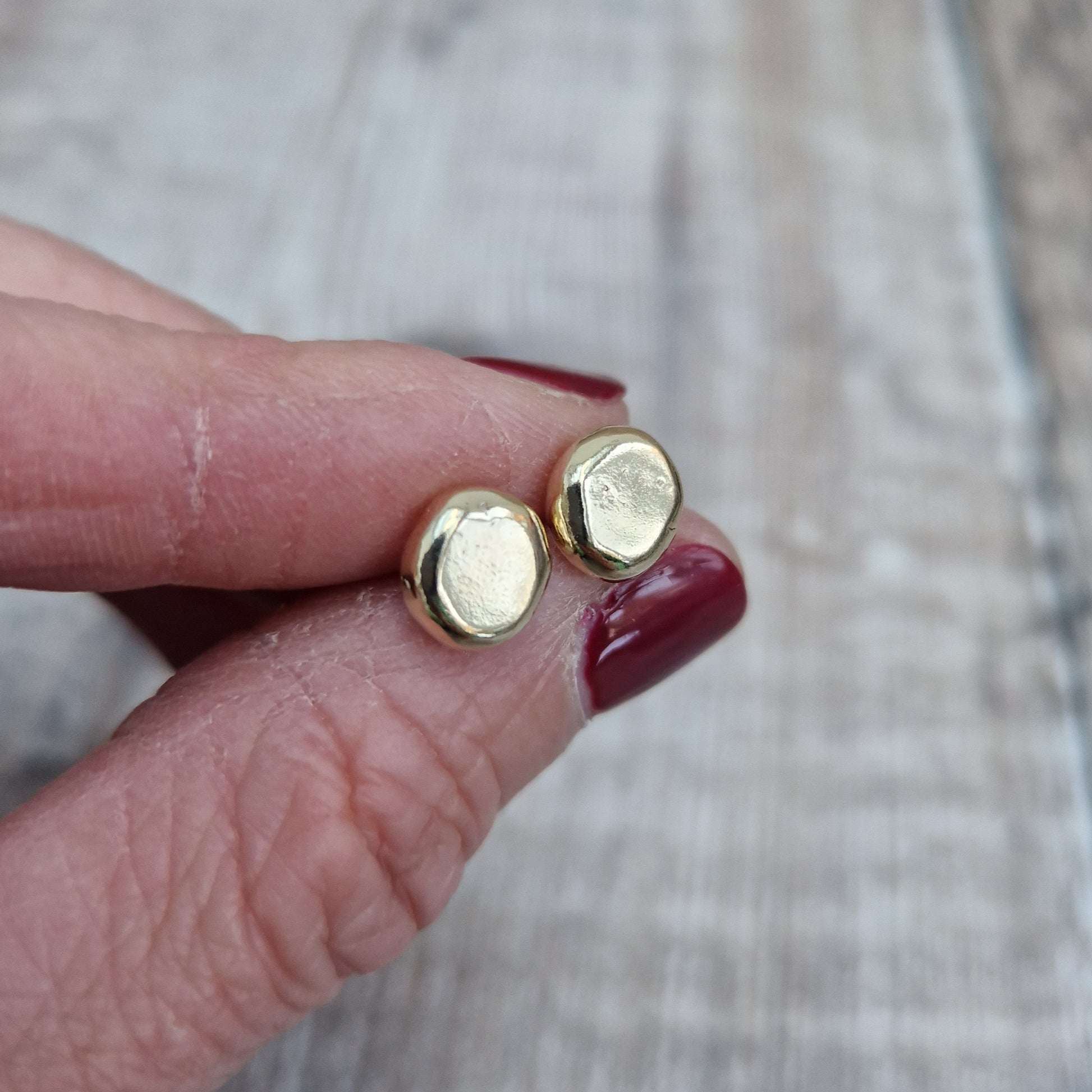 9ct gold pebble shape stud earrings. Recycled 9ct gold melted into a smooth, imperfect round pebble shape with small imperfections on the surface of the gold to provide subtle interest. Each pebble shape measuring approximately 8mm x 7mm, mounted on gold earring bar.