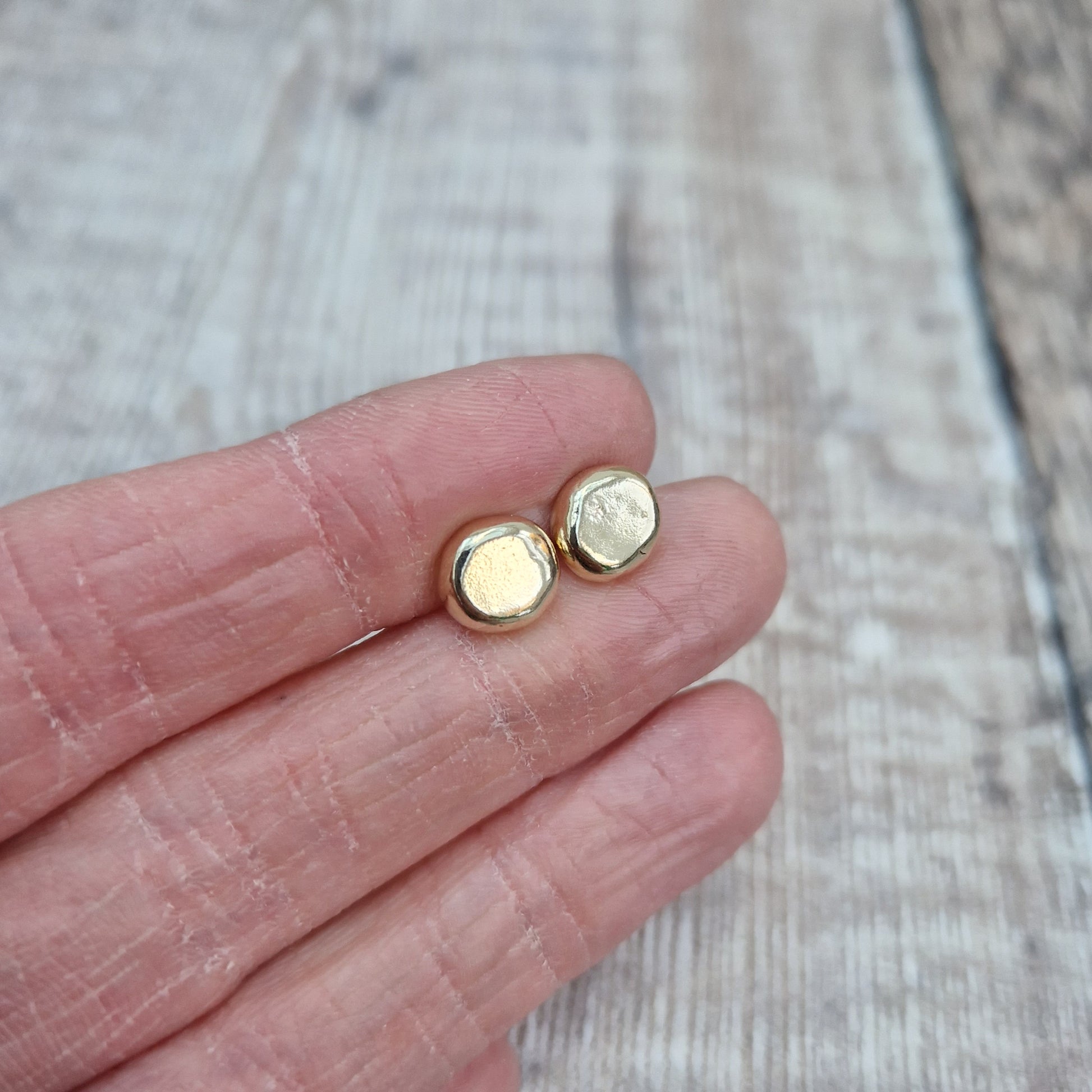 9ct gold pebble shape stud earrings. Recycled 9ct gold melted into a smooth, imperfect round pebble shape with small imperfections on the surface of the gold to provide subtle interest. Each pebble shape measuring approximately 8mm x 7mm, mounted on gold earring bar.