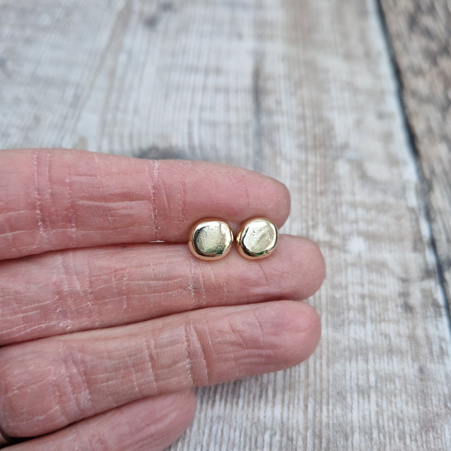 9ct gold pebble shape stud earrings. Recycled 9ct gold melted into a smooth, imperfect round pebble shape with small imperfections on the surface of the gold to provide subtle interest. Each pebble shape measuring approximately 8mm x 7mm, mounted on gold earring bar.