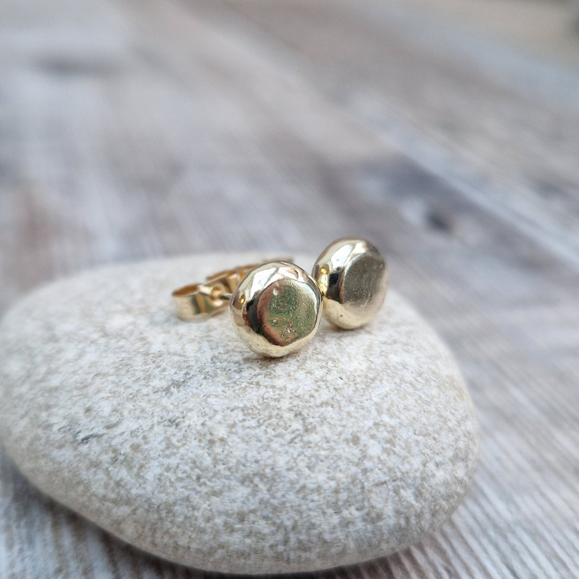 9ct gold pebble shape stud earrings. Recycled 9ct gold melted into a smooth, imperfect round pebble shape with small imperfections on the surface of the gold to provide subtle interest. Each pebble shape measuring approximately 8mm x 7mm, mounted on gold earring bar.