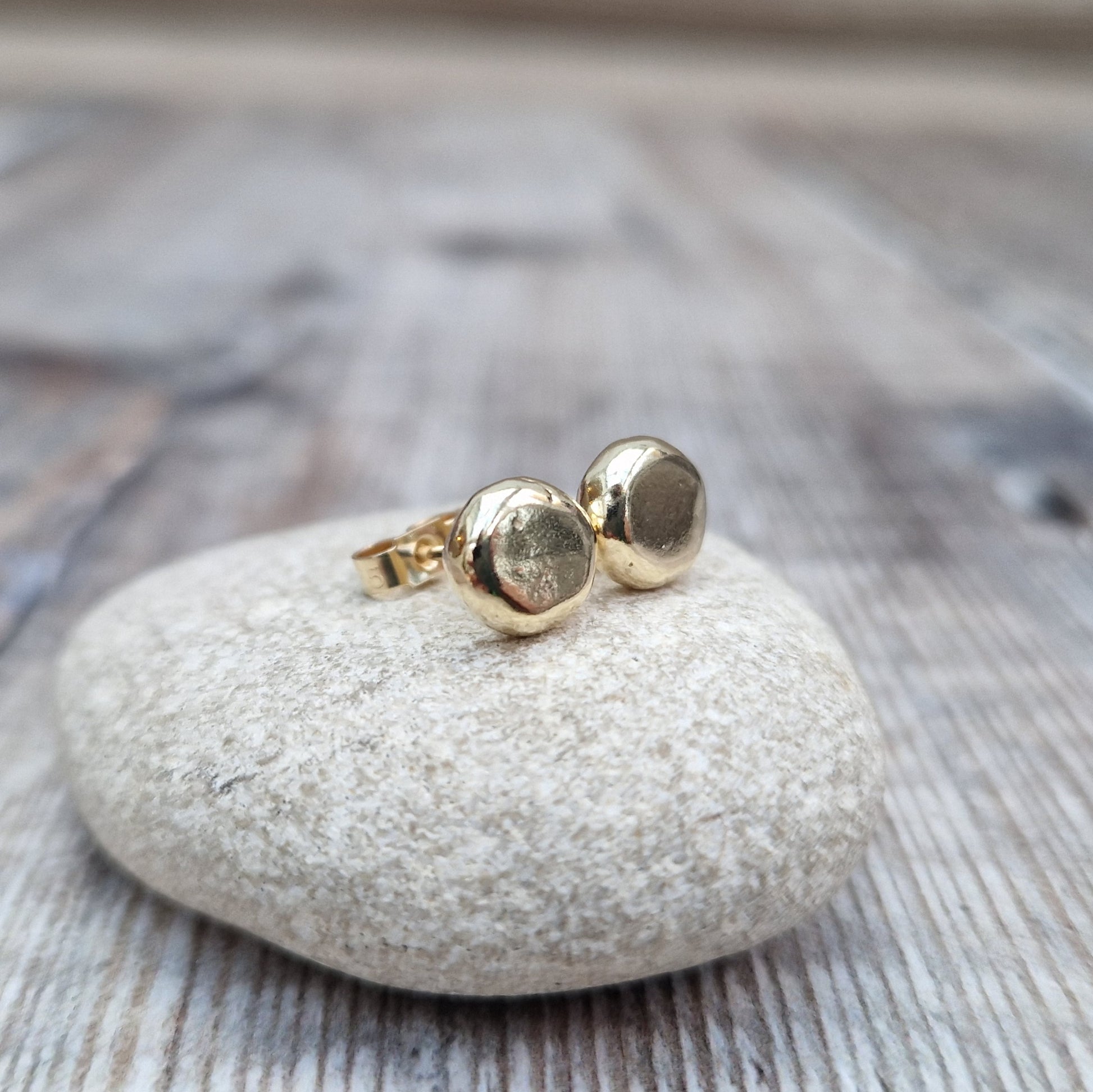 9ct gold pebble shape stud earrings. Recycled 9ct gold melted into a smooth, imperfect round pebble shape with small imperfections on the surface of the gold to provide subtle interest. Each pebble shape measuring approximately 8mm x 7mm, mounted on gold earring bar.