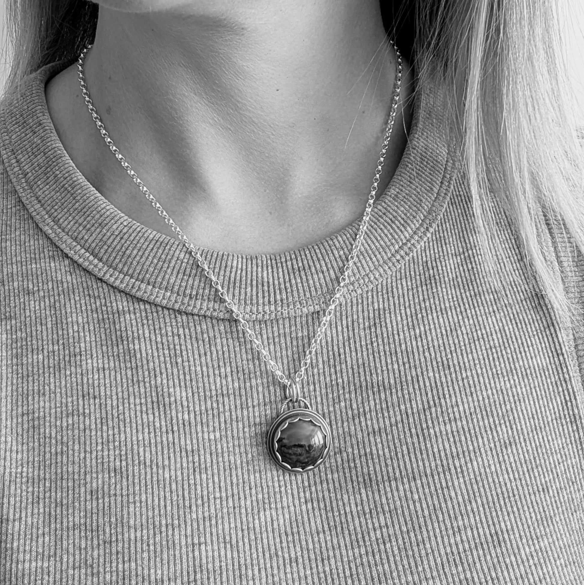 A black and white image of a model wearing the Green Hava Ridge Jasper necklace, showcasing how the pendant hangs elegantly on the chest.
