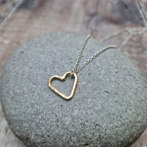 Open heart shaped 9ct gold pendant hangs from sterling silver chain necklace. Heart measures approximately 15mm diameter. Slightly hammered texture on the pendant.