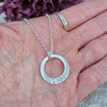 Load image into Gallery viewer, Sterling Silver ‘LOVE’ necklace. Silver disc with offset hole in centre, looks like a thick circle. Attached via two small silver hoops to silver chain. On thicker part of disc, inscription wording hammered into the silver reads LOVE in capitals. Disc measures approximately 20 mm in diameter. Chain length 18 inches.