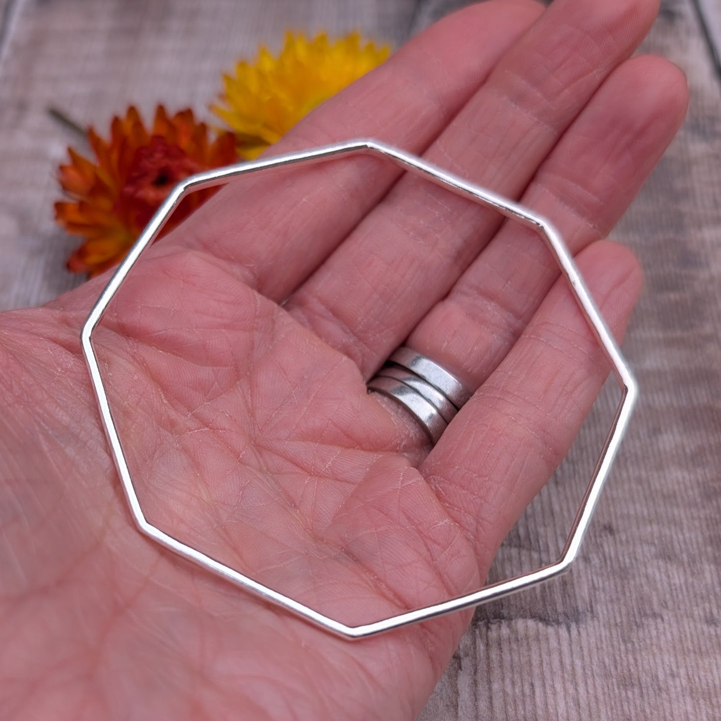 The handmade sterling silver octagon bangle resting in an open palm, showing its full shape and lightweight construction.