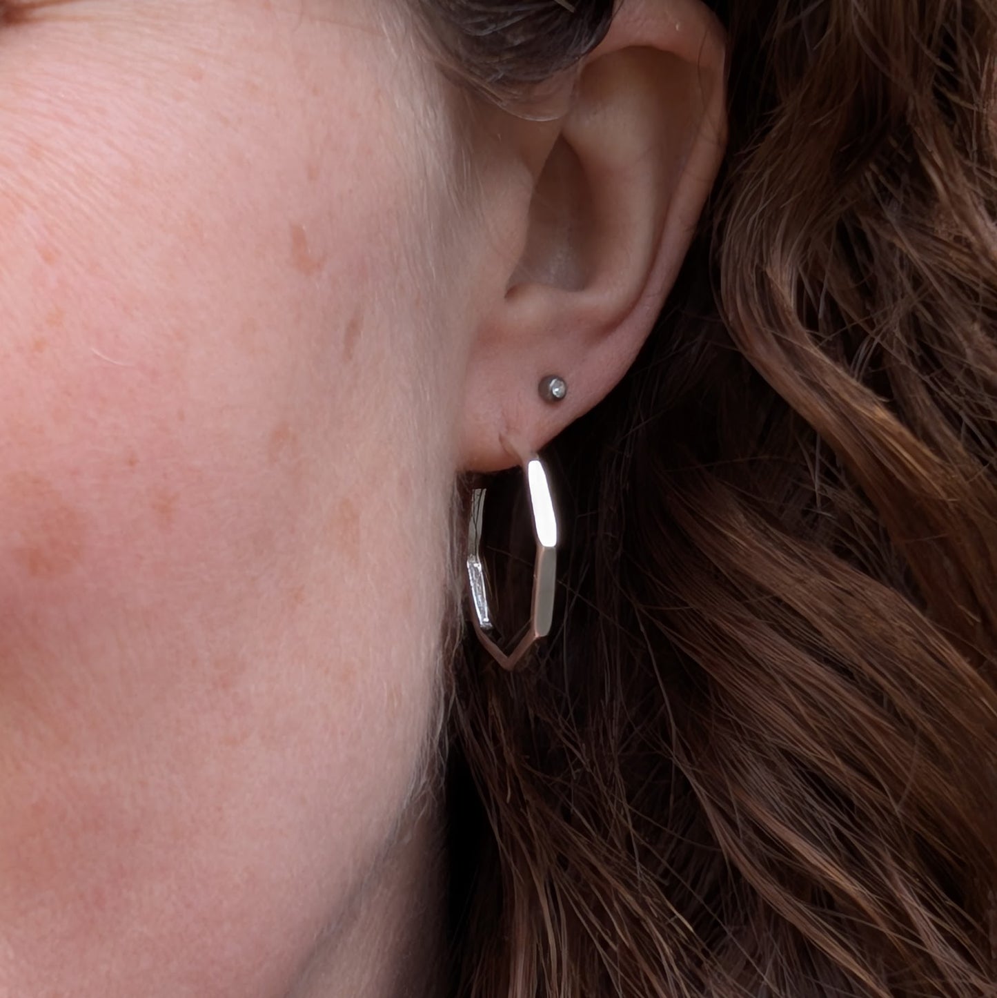 Octagon hoop earring worn on an ear, showing its lightweight and modern geometric shape in polished sterling silver.