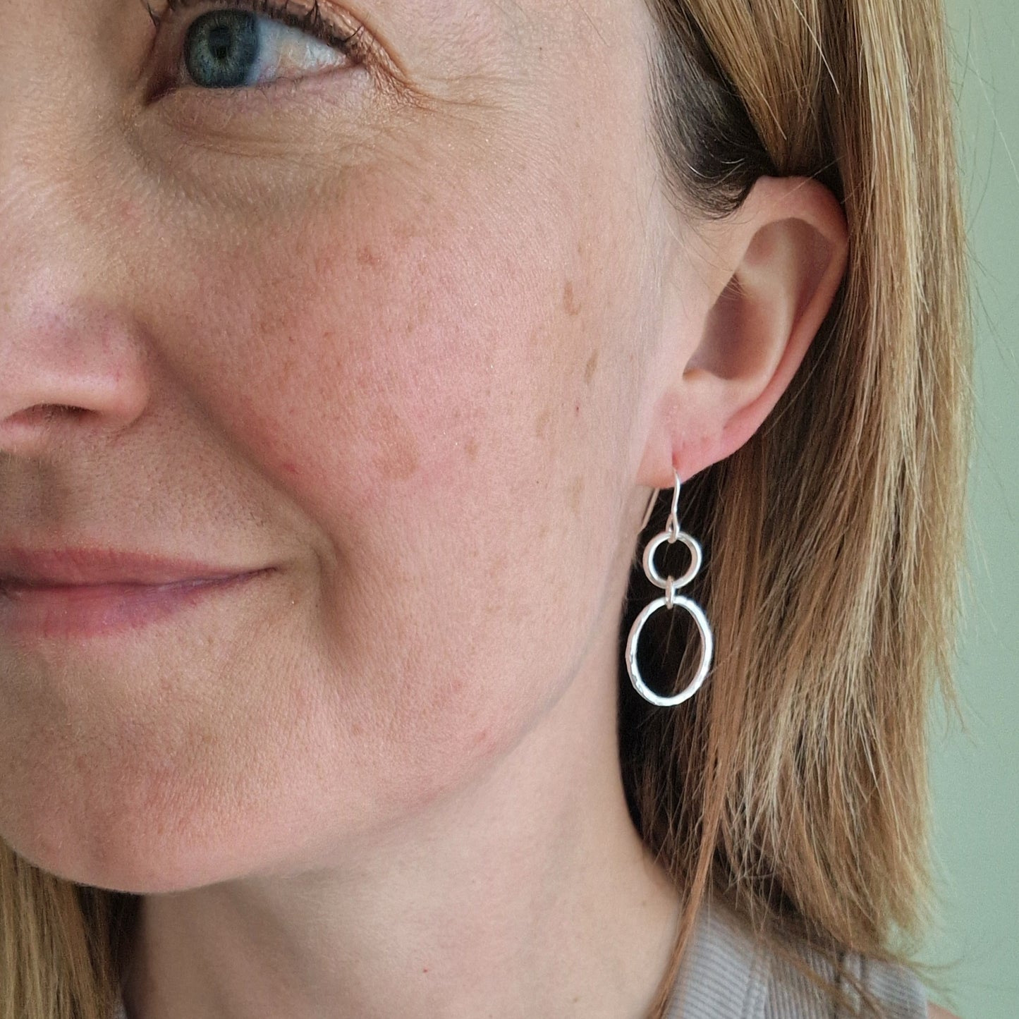 Each earring has one Sterling Silver open circle suspended from silver earring wire. A hammered texture silver open oval hangs from the open circle via a small circle link.