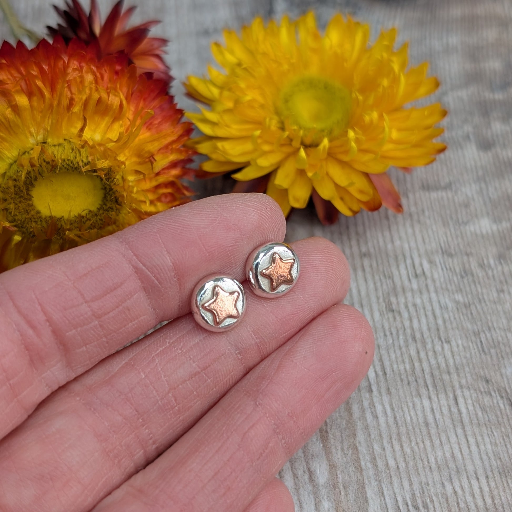 Stud Earrings in Hand
A pair of recycled sterling silver and copper star stud earrings held in a hand, showcasing their small, organic shape. Each silver pebble is formed by melting scrap silver, with a contrasting copper star. Sustainable, handmade jewellery for everyday wear.