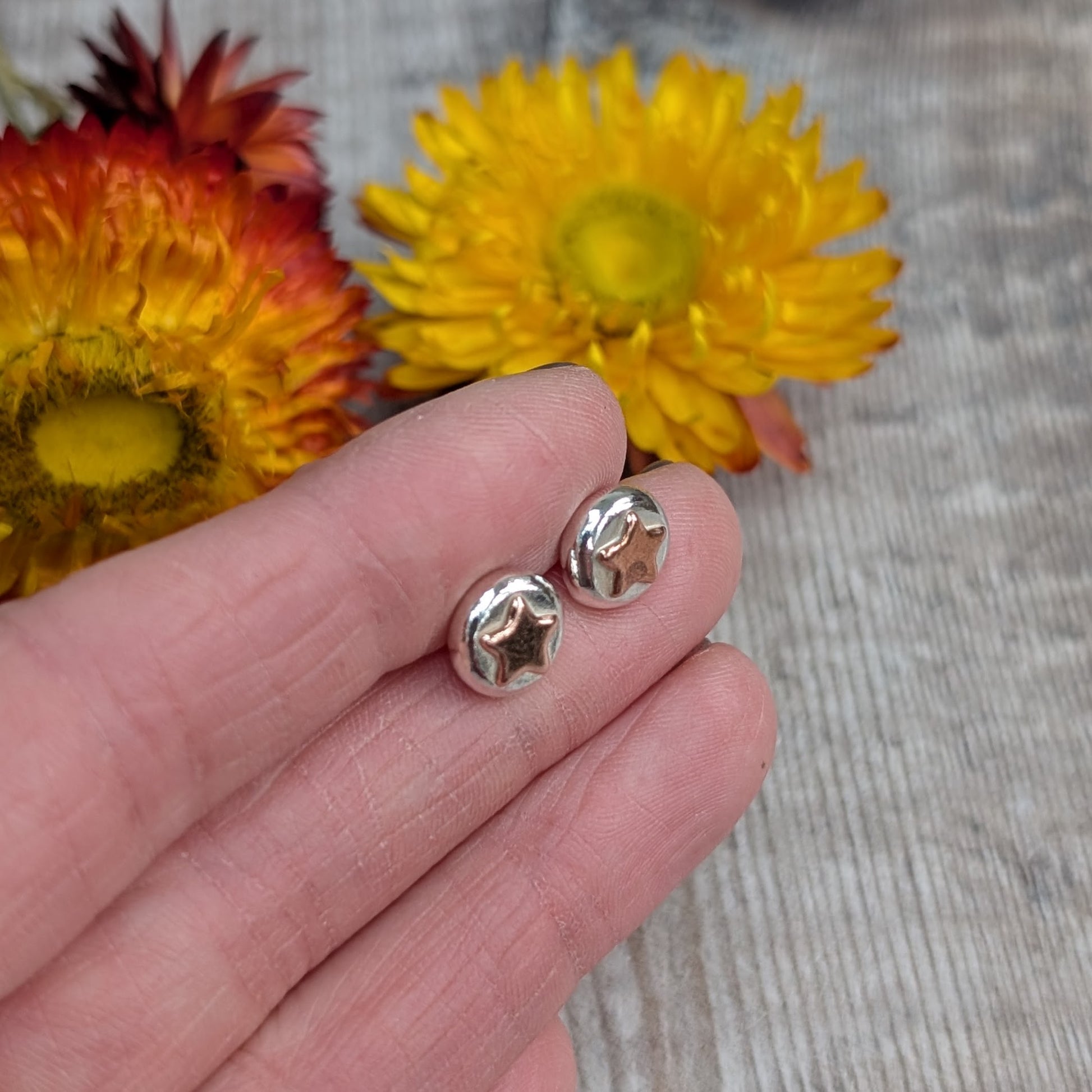 Stud Earrings in Hand
A pair of recycled sterling silver and copper star stud earrings held in a hand, showcasing their small, organic shape. Each silver pebble is formed by melting scrap silver, with a contrasting copper star. Sustainable, handmade jewellery for everyday wear.