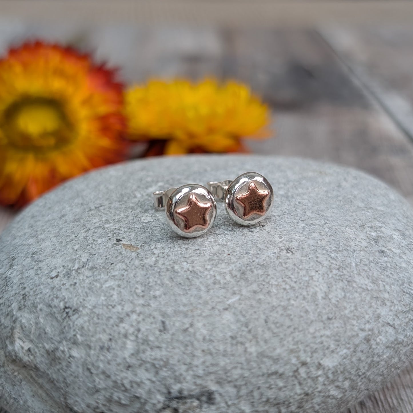 Stud Earrings on a Pebble
Close-up of handmade recycled sterling silver stud earrings with copper star details, resting on a smooth grey stone. The silver pebbles have an organic shape, with a warm copper star at the centre. Eco-friendly, sustainable jewellery, handmade in the UK.