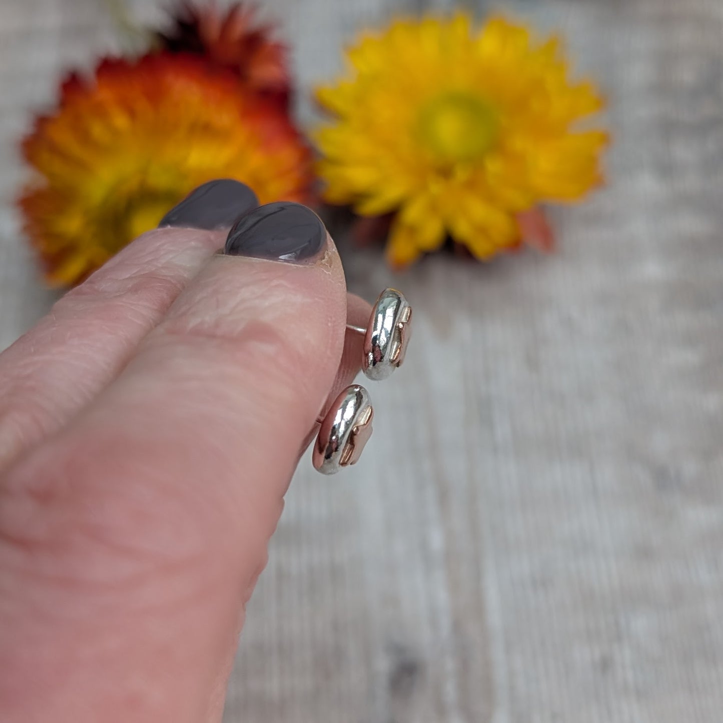 Stud Earrings in Hand
A pair of recycled sterling silver and copper star stud earrings held in a hand, showcasing their small, organic shape. Each silver pebble is formed by melting scrap silver, with a contrasting copper star. Sustainable, handmade jewellery for everyday wear.