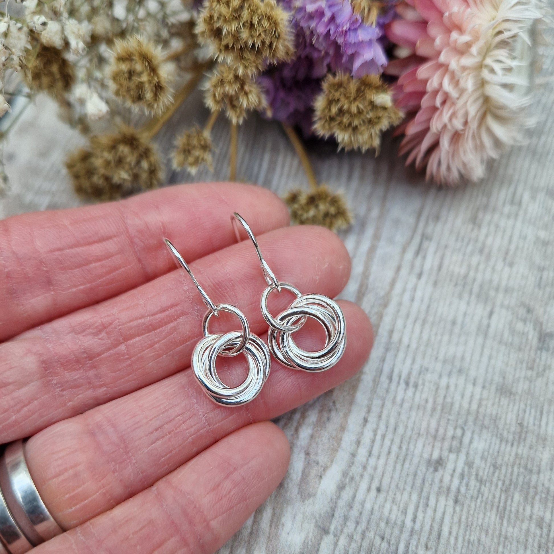 Each earring is three open circle rings entwined as a Russian ring suspended from silver earring wire via a silver circle link.