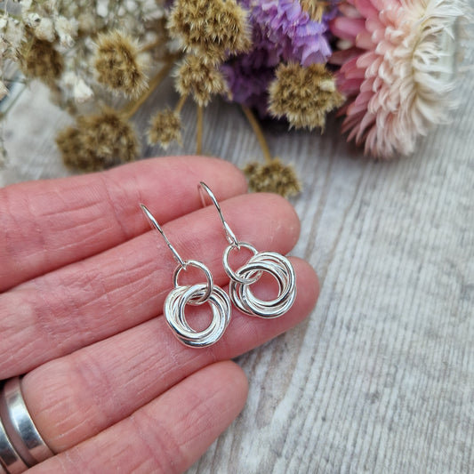 Each earring is three open circle rings entwined as a Russian ring suspended from silver earring wire via a silver circle link.