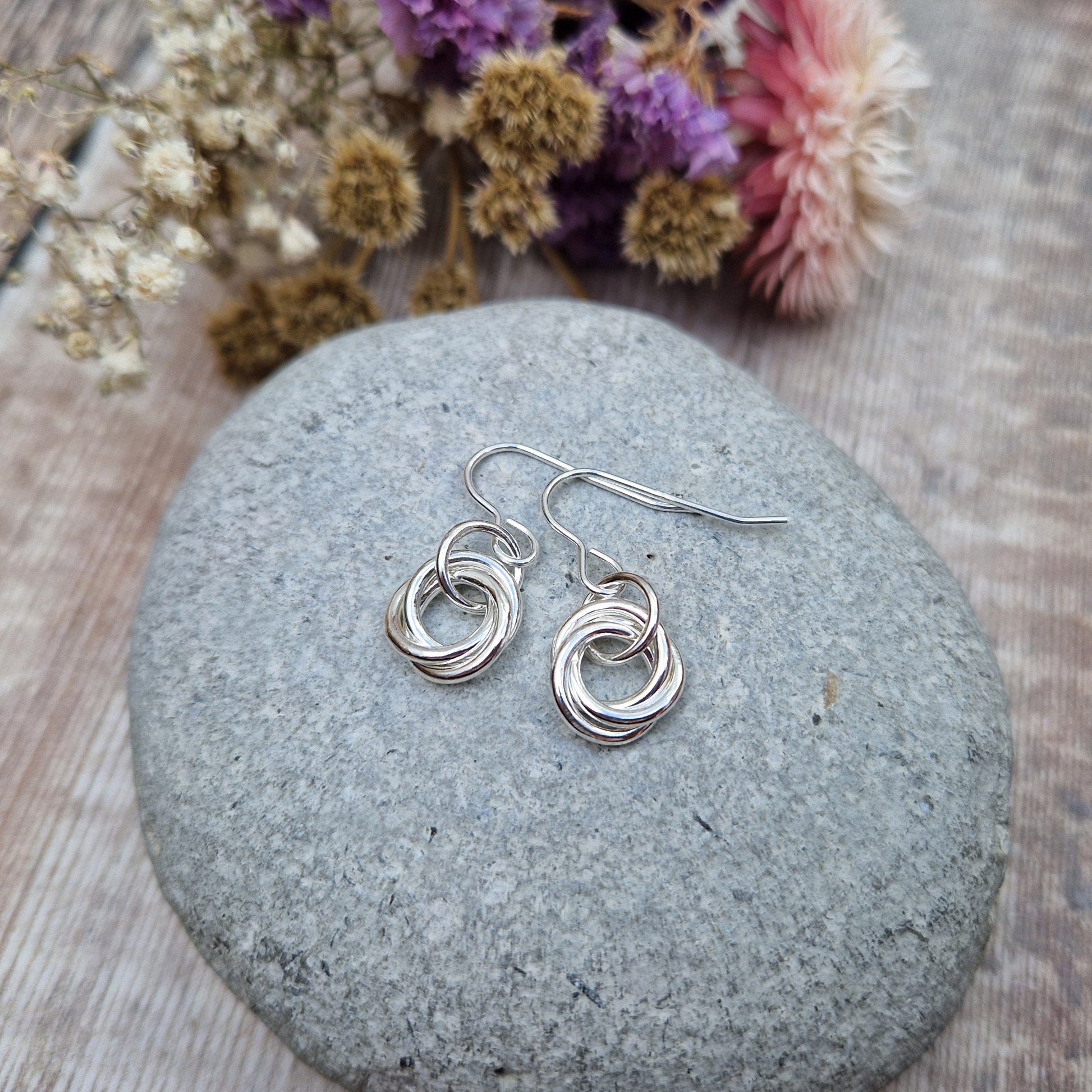 Each earring is three open circle rings entwined as a Russian ring suspended from silver earring wire via a silver circle link.