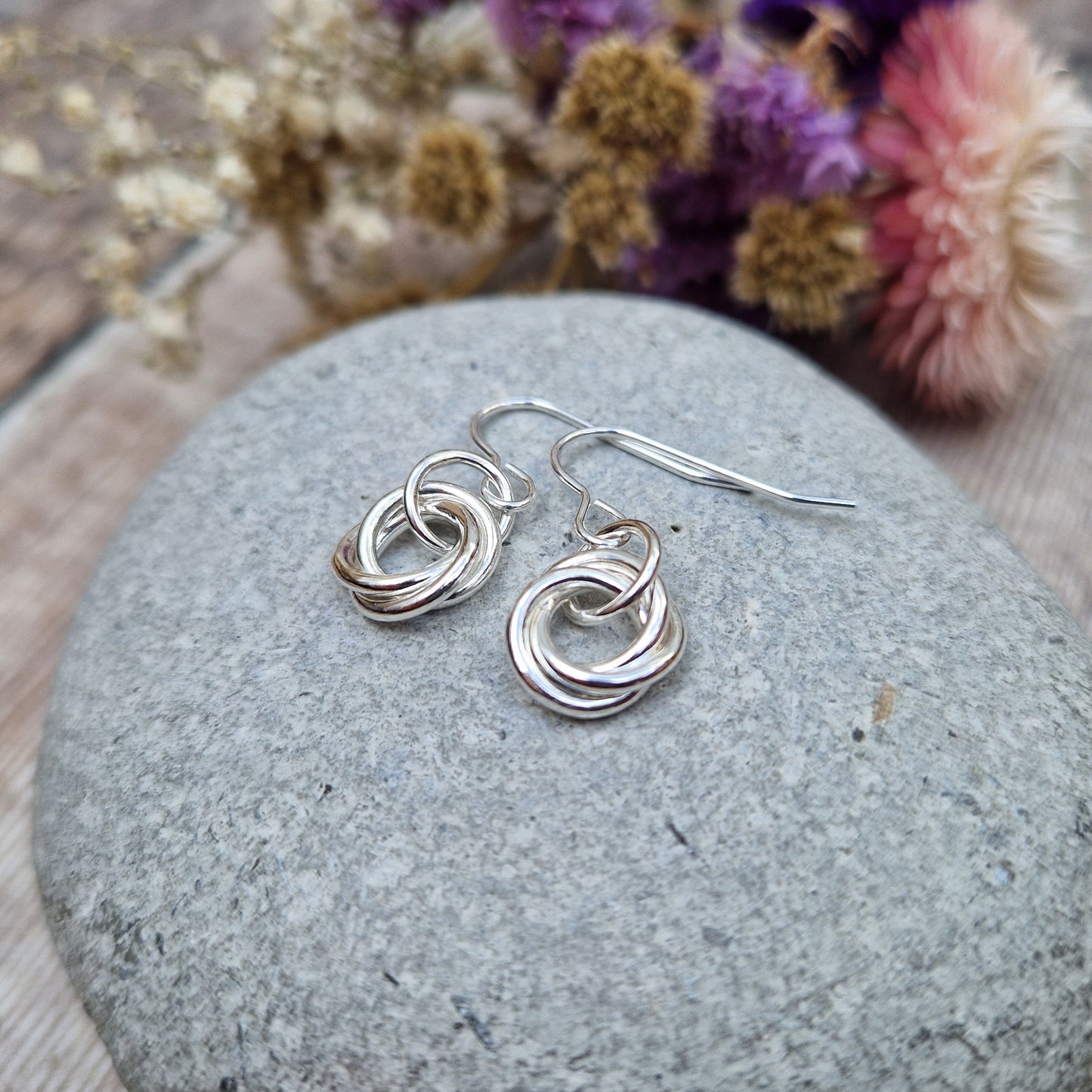 Each earring is three open circle rings entwined as a Russian ring suspended from silver earring wire via a silver circle link.