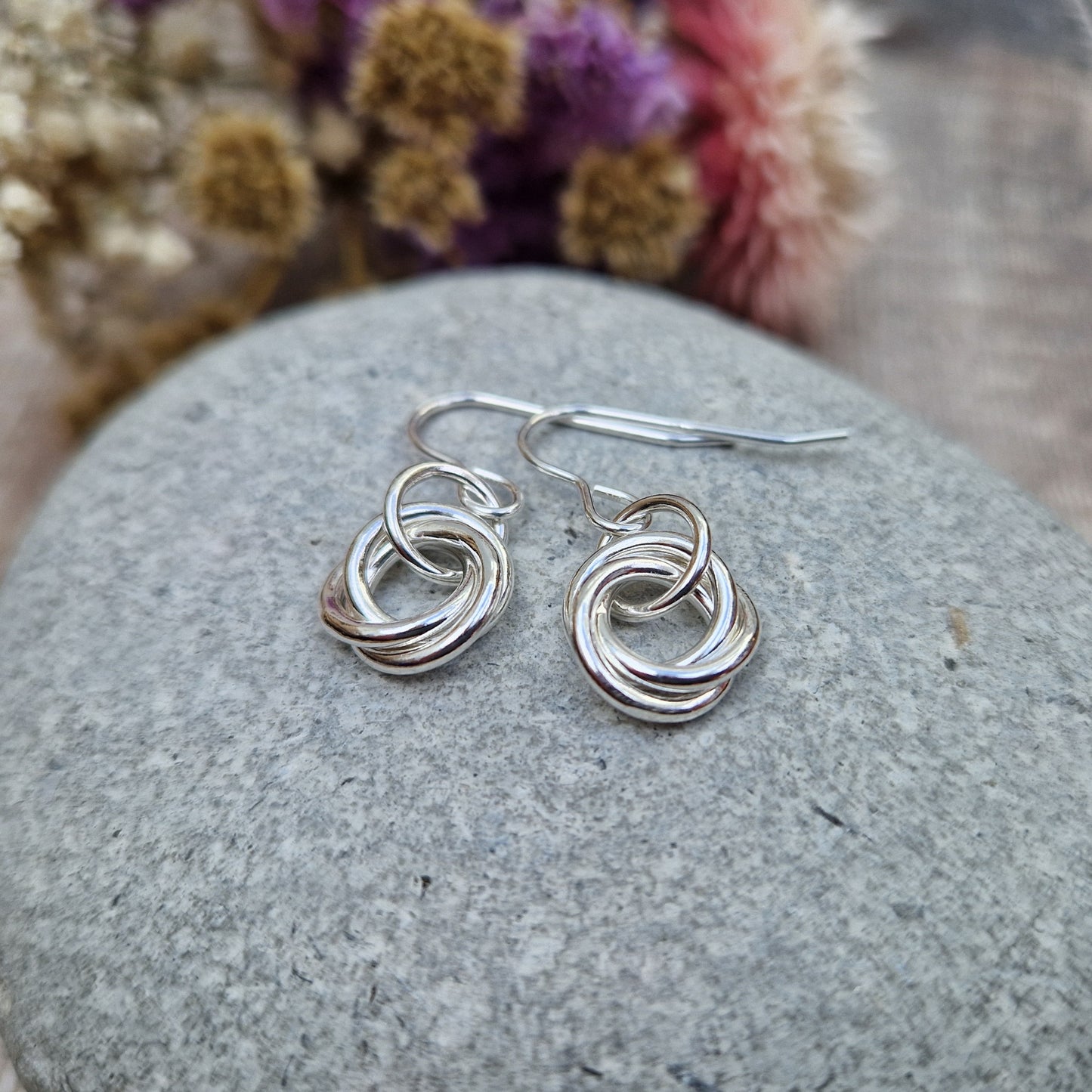 Each earring is three open circle rings entwined as a Russian ring suspended from silver earring wire via a silver circle link.