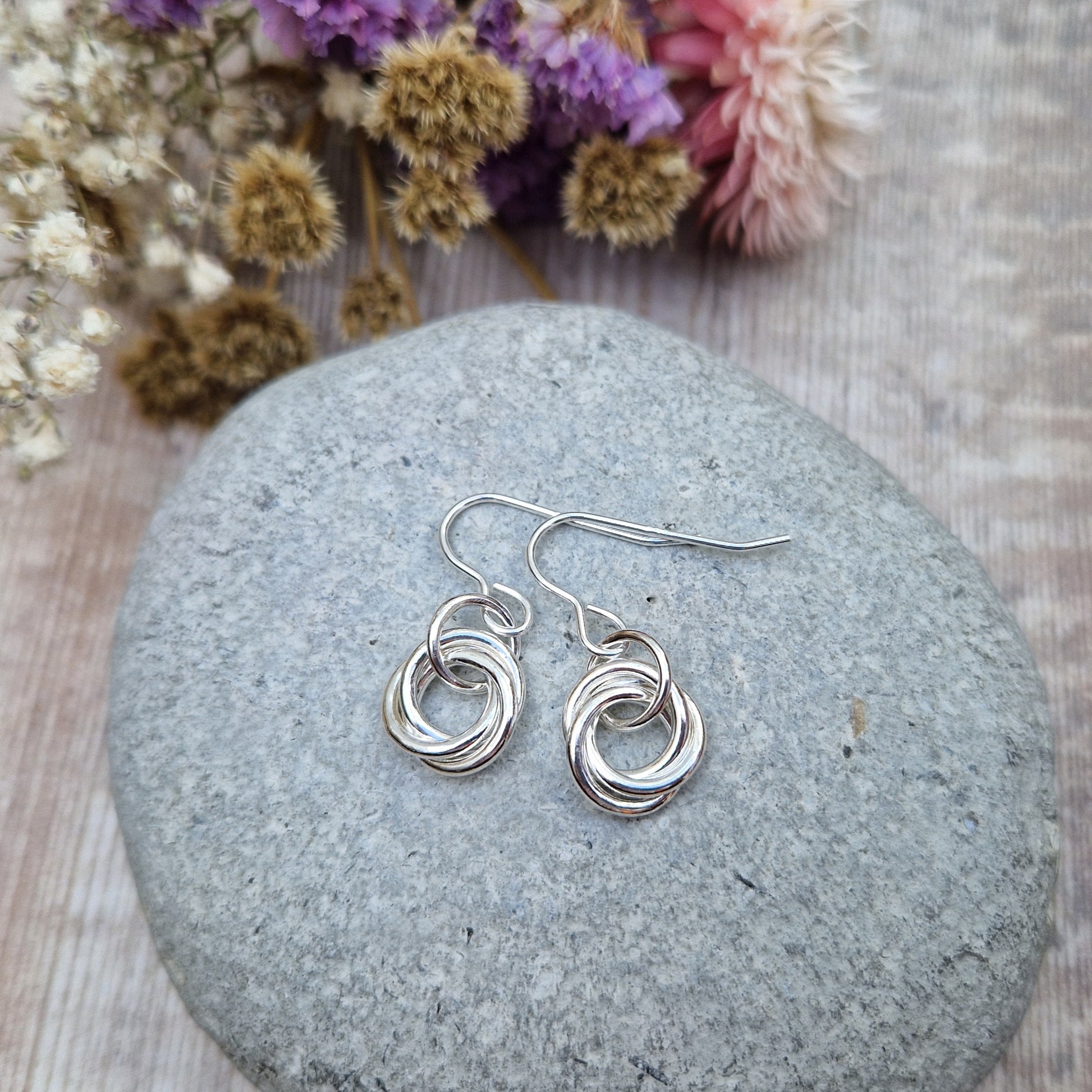 Each earring is three open circle rings entwined as a Russian ring suspended from silver earring wire via a silver circle link.