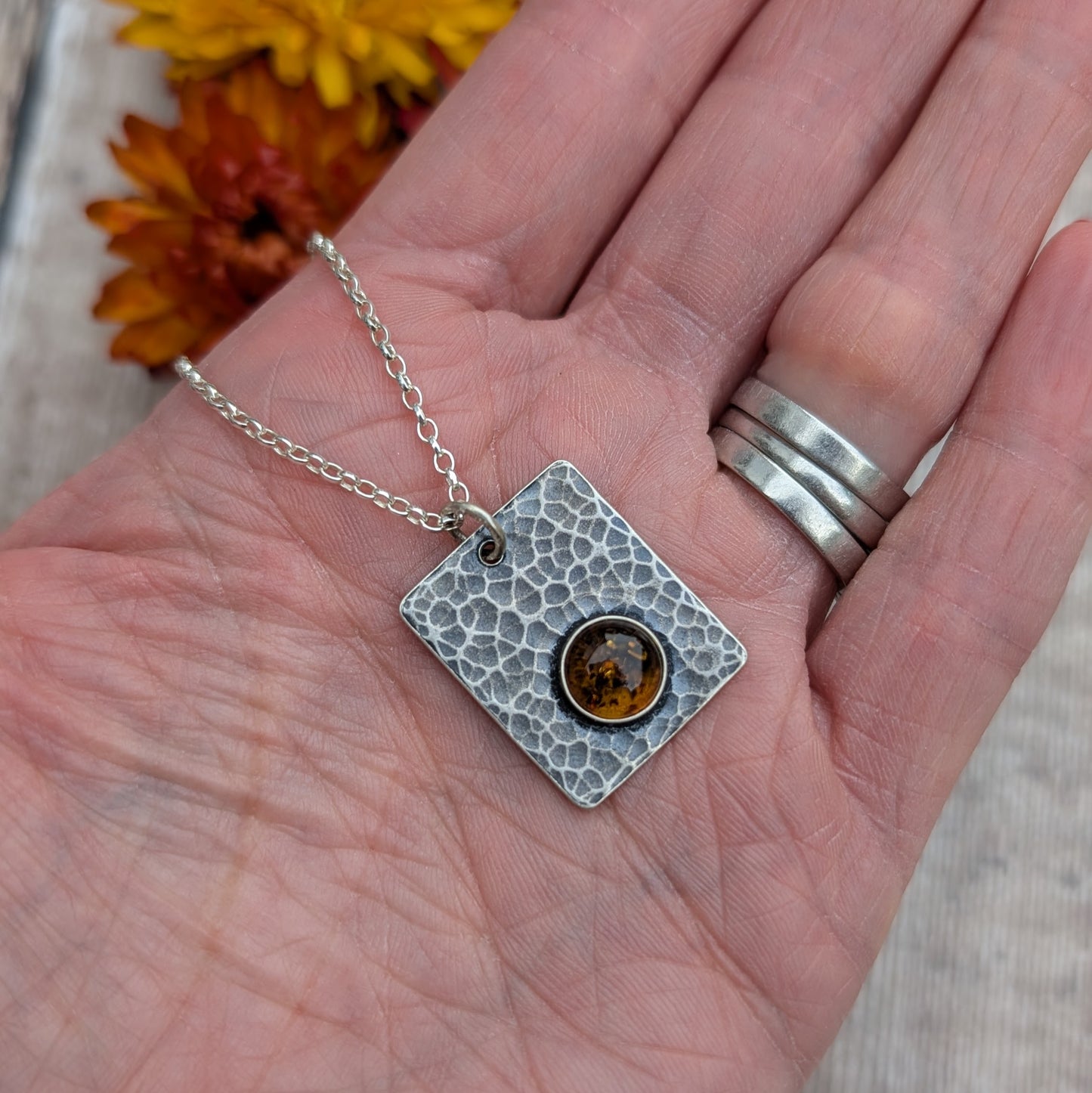 Silver Rectangle Necklace with Amber displayed in the palm of a hand, showing its size and detail.
