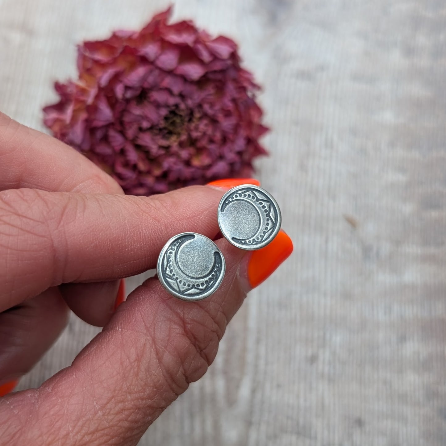 Close-up of oxidised silver moon disc earrings with detailed crescent moon pattern.