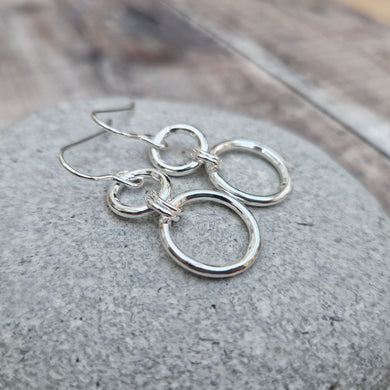 Stirling Silver two circle drop earrings. Each earring has one smaller silver open circle attached to silver earring wire. Attached to the small open circle via two small hoops is a larger open silver circle measuring 15mm in diameter. Approximately 35mm drop including earring hook providing lots of movement.