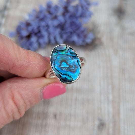 Close-up of the Silver Blue Paua Shell Ring held between fingers highlighting the natural blue pattern of the Paua Shell.