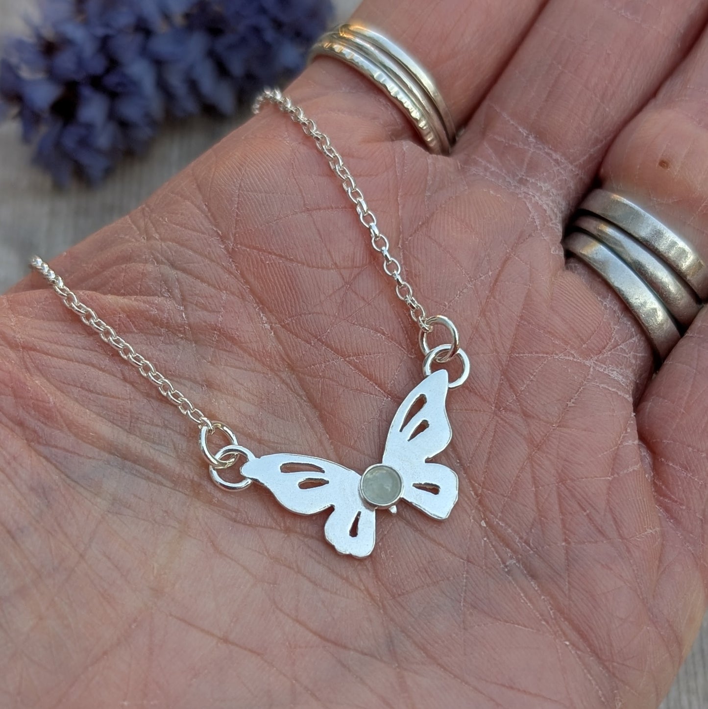 Close-up of Silver Butterfly Necklace with Aquamarine in a hand highlighting the small central stone and cut-out wings