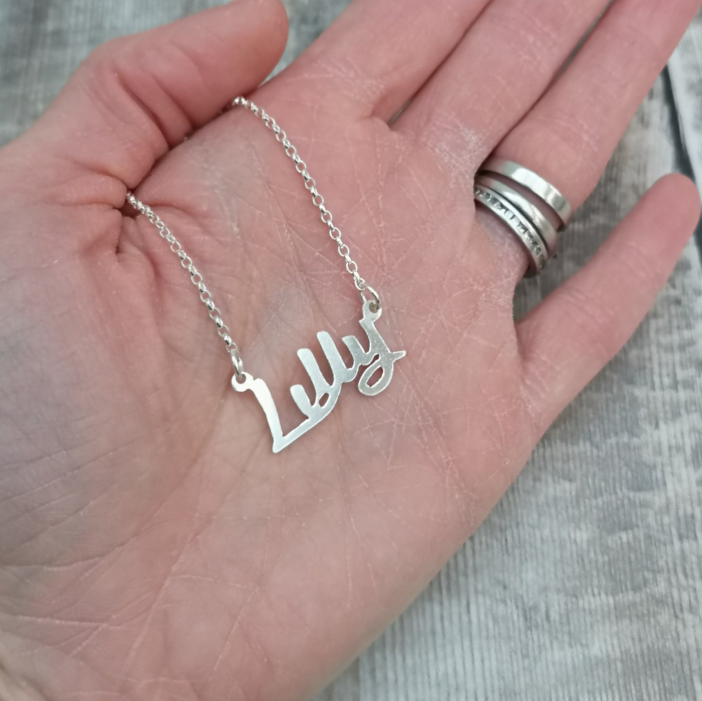 silver personalised name necklace shown displayed on the palm of a hand.