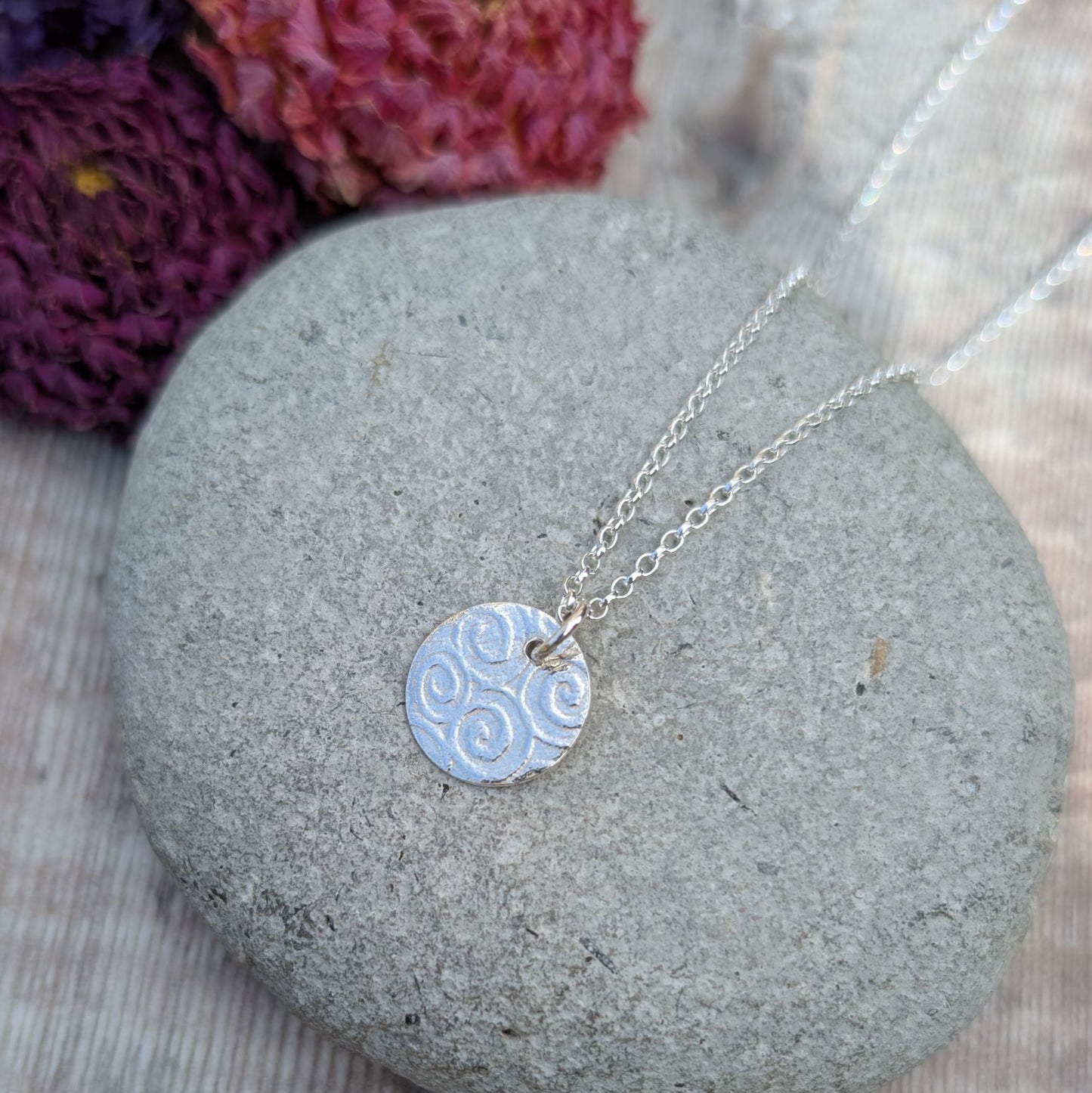 Close-up of Silver Spiral Pattern Disc Necklace showing spiral texture on a small round silver disc on a chain