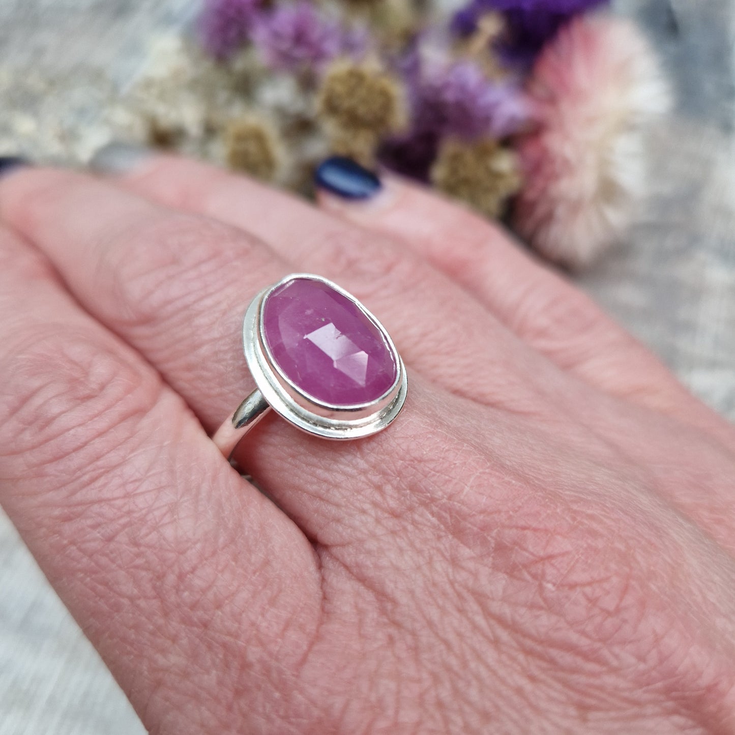 Red Sapphire oval gemstone UK Size R, with diamond cut texture, set in simple silver bezel mounted on top of Sterling Silver band approx. 2mm wide. Sapphire stone is a cloudy mauve colour.
