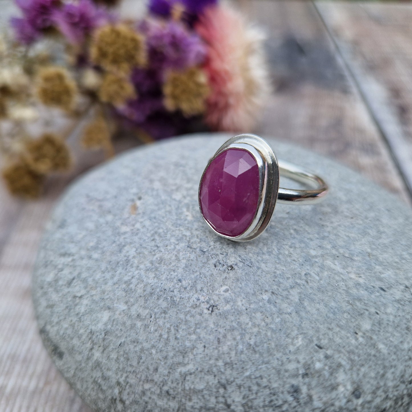 Red Sapphire oval gemstone UK Size R, with diamond cut texture, set in simple silver bezel mounted on top of Sterling Silver band approx. 2mm wide. Sapphire stone is a cloudy mauve colour.