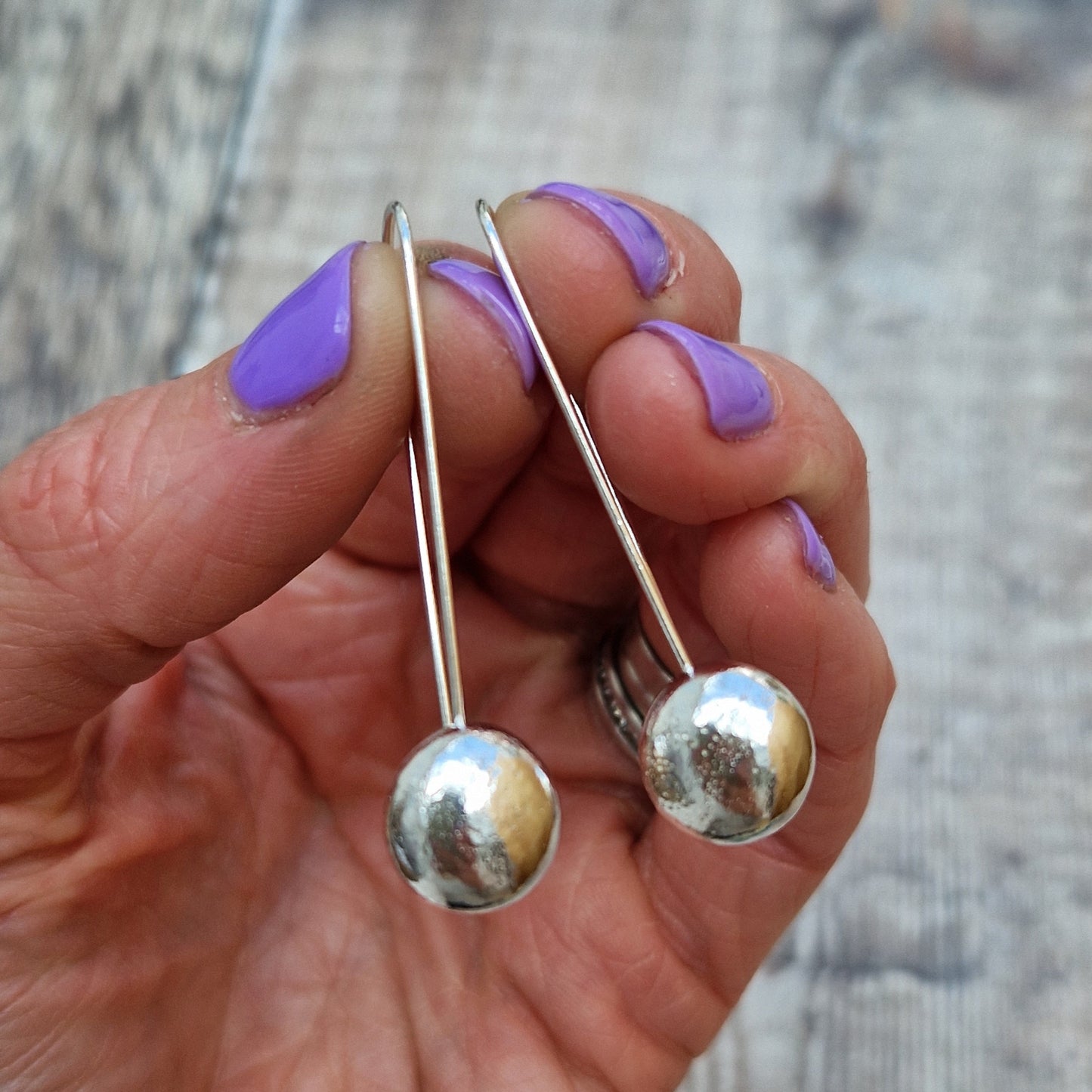 Each earring is a smooth Sterling Silver pebble shape welded onto a long straight earring wire loop.