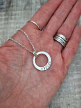 Load image into Gallery viewer, Sterling Silver ‘STRONG’ necklace. Silver disc with offset hole in centre, looks like a thick circle. Attached via two small silver hoops to silver chain. On thicker part of disc, inscription wording hammered into the silver reads STRONG in capitals. Disc measures approximately 20 mm in diameter. Chain length 16, 18 or 20 inches.