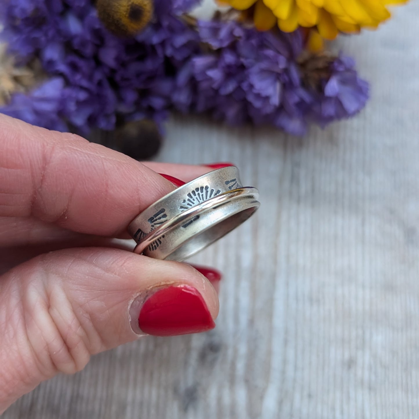 Wide oxidised Sterling Silver band with stamped sunrise pattern. Additional 2mm wide silver band around the middle that spins independently.
